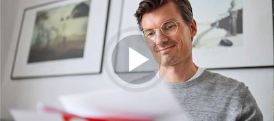 Lächelnder Mann schaut ein Video auf einem Tablet.