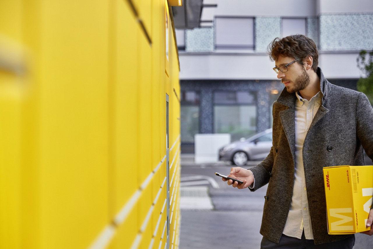 Mann mit Handy an der Packstation