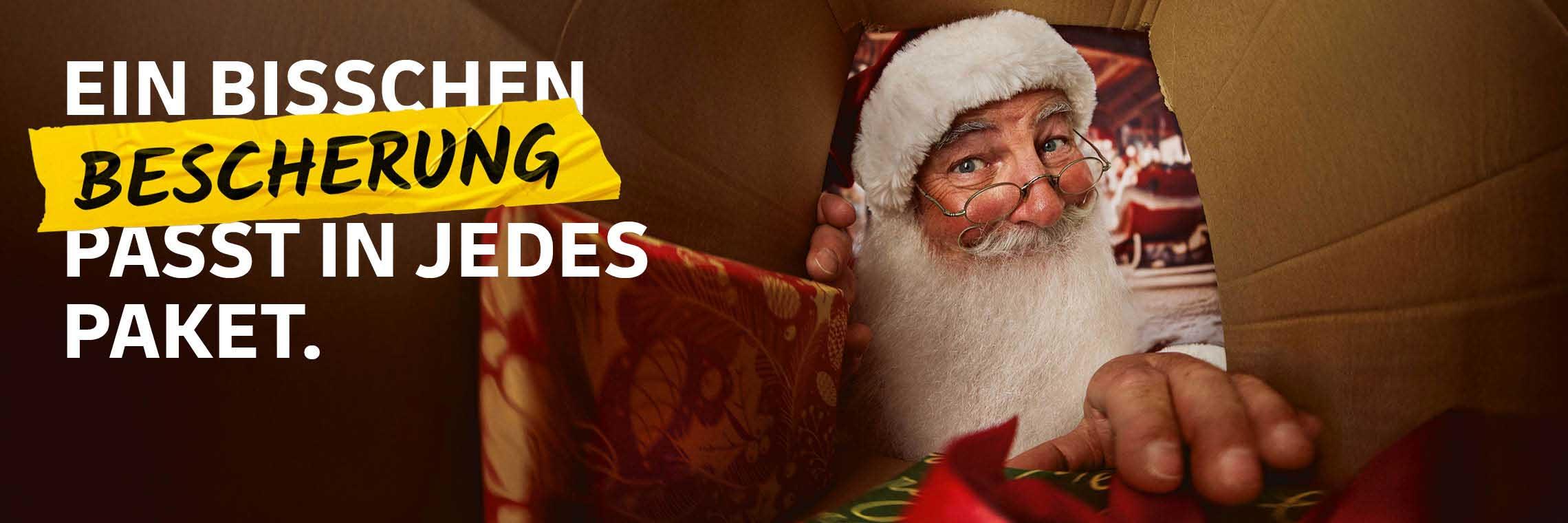 Der Weihnachtsmann hinterlegt ein Paket am Ablageort in einem Carport. Im Hintergrund ist sein Schlitten zu sehen. Schriftzug: Ein bisschen Bescherung passt in jedes Paket.