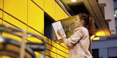 Woman with parcel in front of DHL Packstation