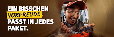 Ein Empfänger packt fröhlich sein Paket aus - denn: Ein bisschen Vorfreude passt in jedes Paket. 
