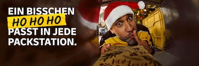 Ein DHL Zusteller mit Weihnachtsmütze legt ein Paket in ein Packstation-Fach. Schriftzug: Ein bisschen Ho Ho Ho passt in jedes Paket.